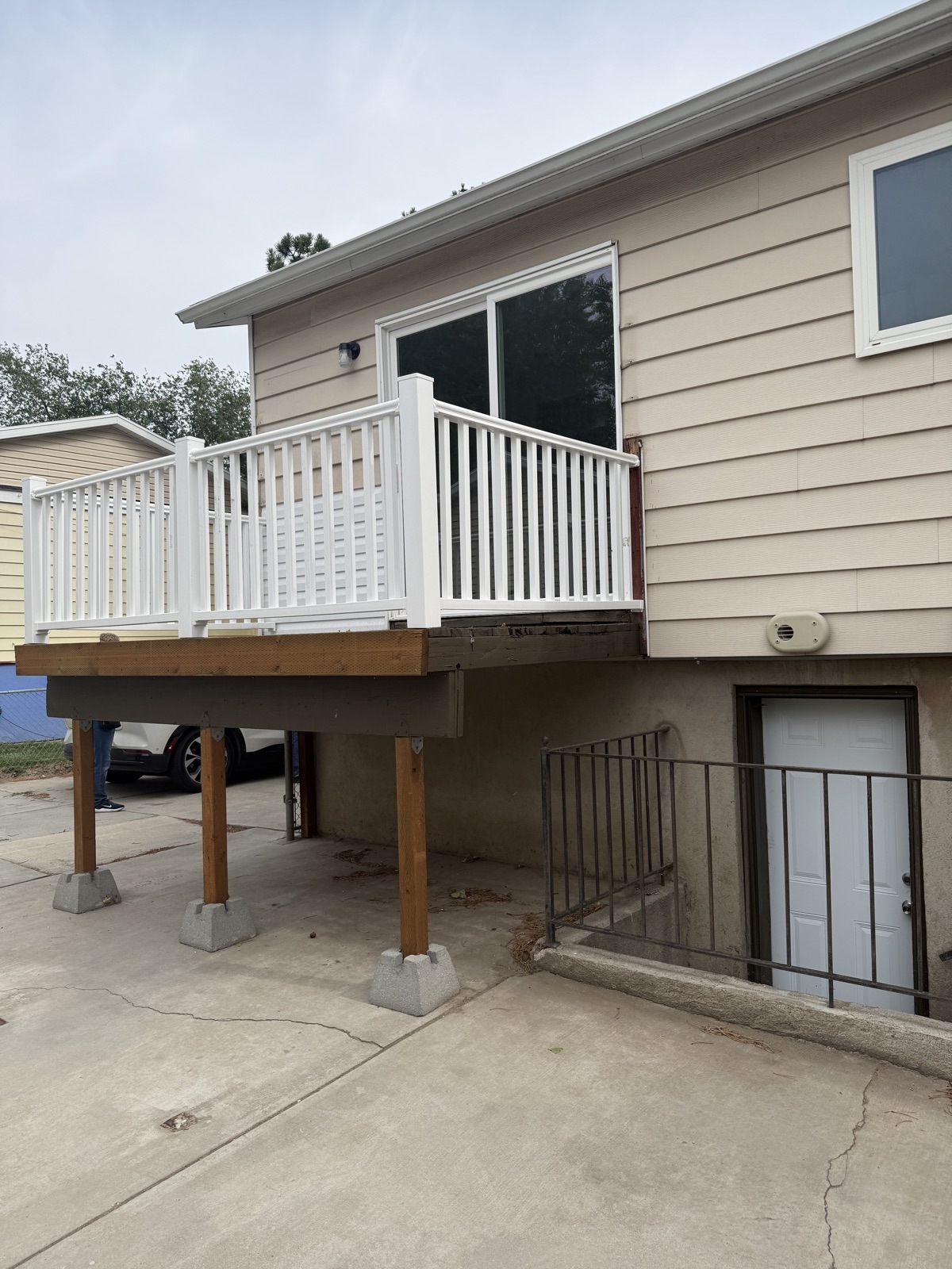 The same deck rebuilt on new timber posts set in concrete footings, with a white vinyl railing